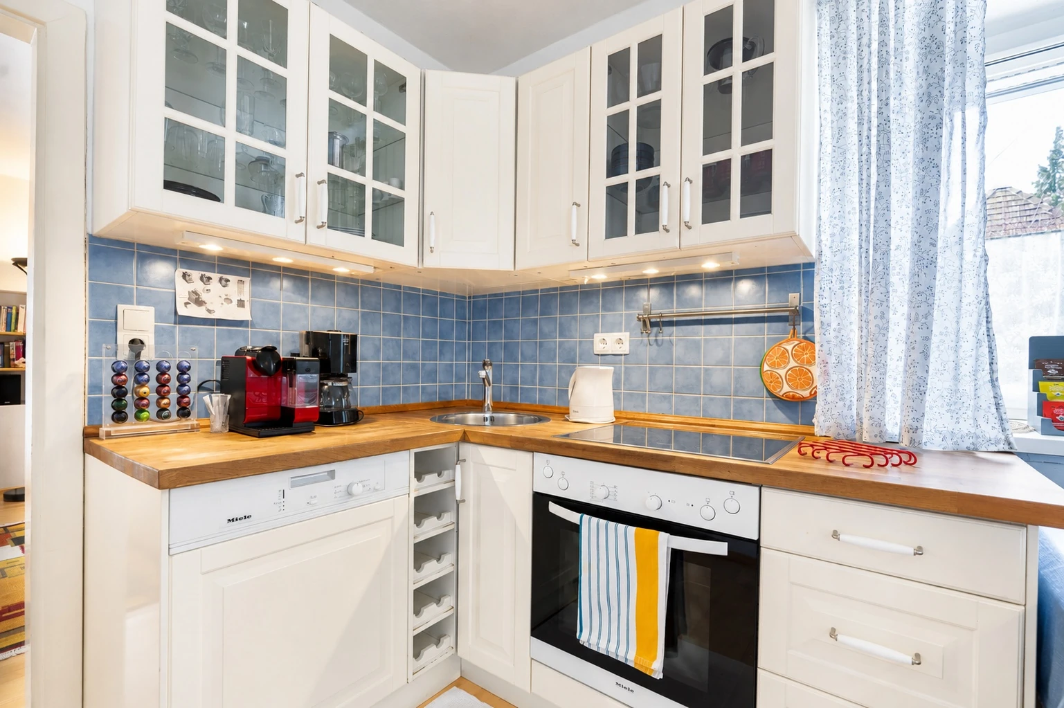 Küche mit weißen Schränken, Backofen und blauem Fliesenspiegel