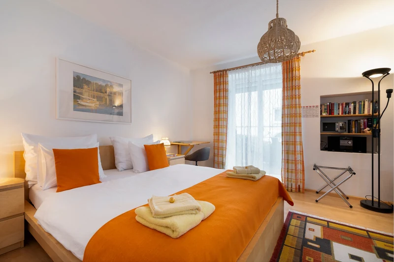 Schlafzimmer mit orangefarbener Tagesdecke