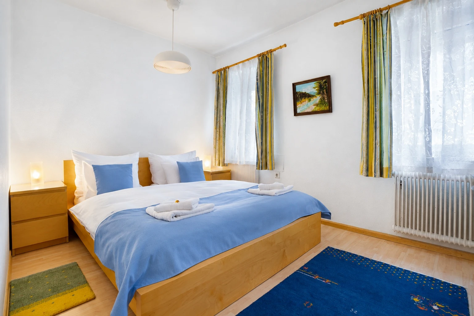 Erstes Schlafzimmer mit Doppelbett und blauer Tagesdecke