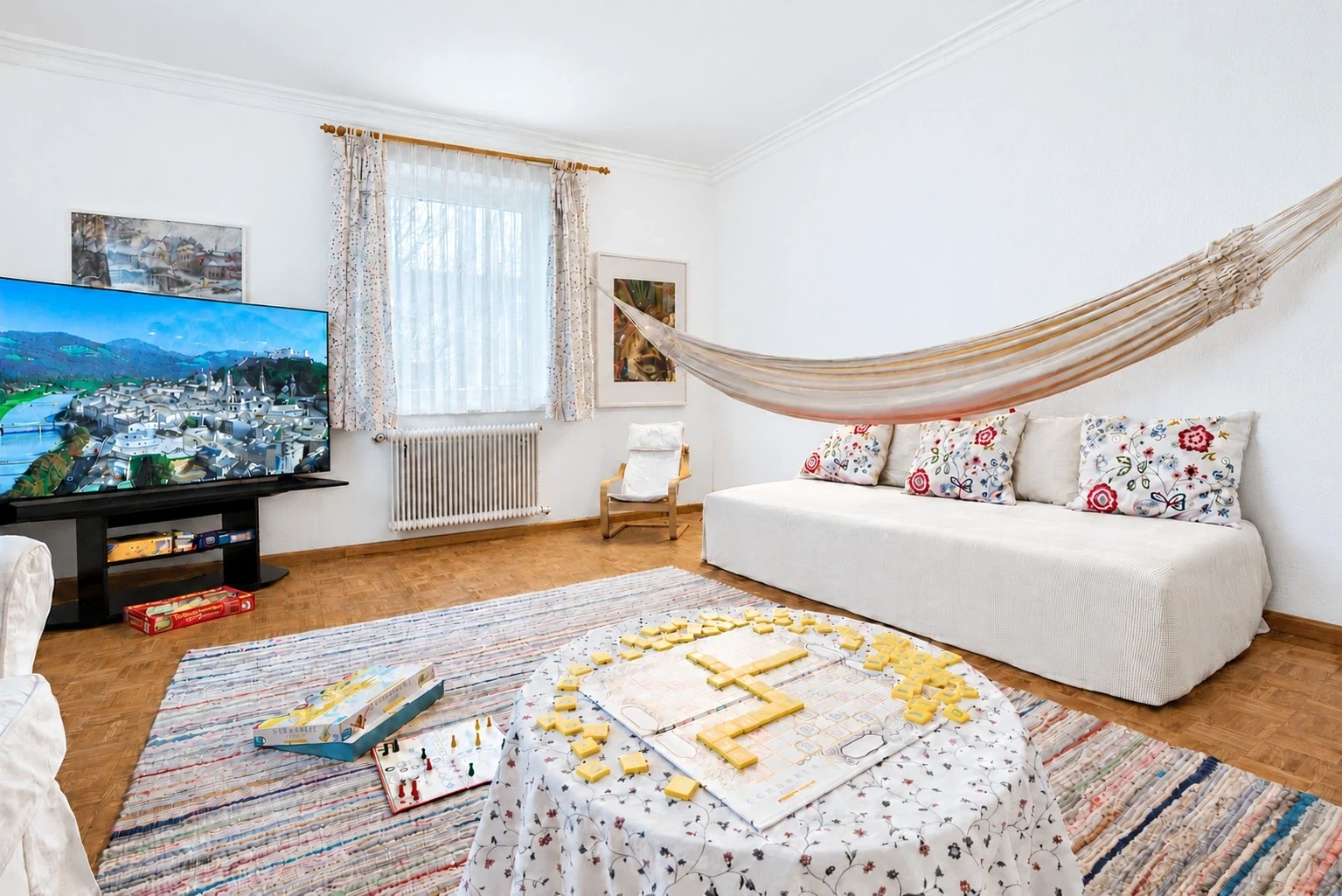 Wohnzimmer mit Hängematte, Fernseher und einem Brettspiel auf dem Tisch