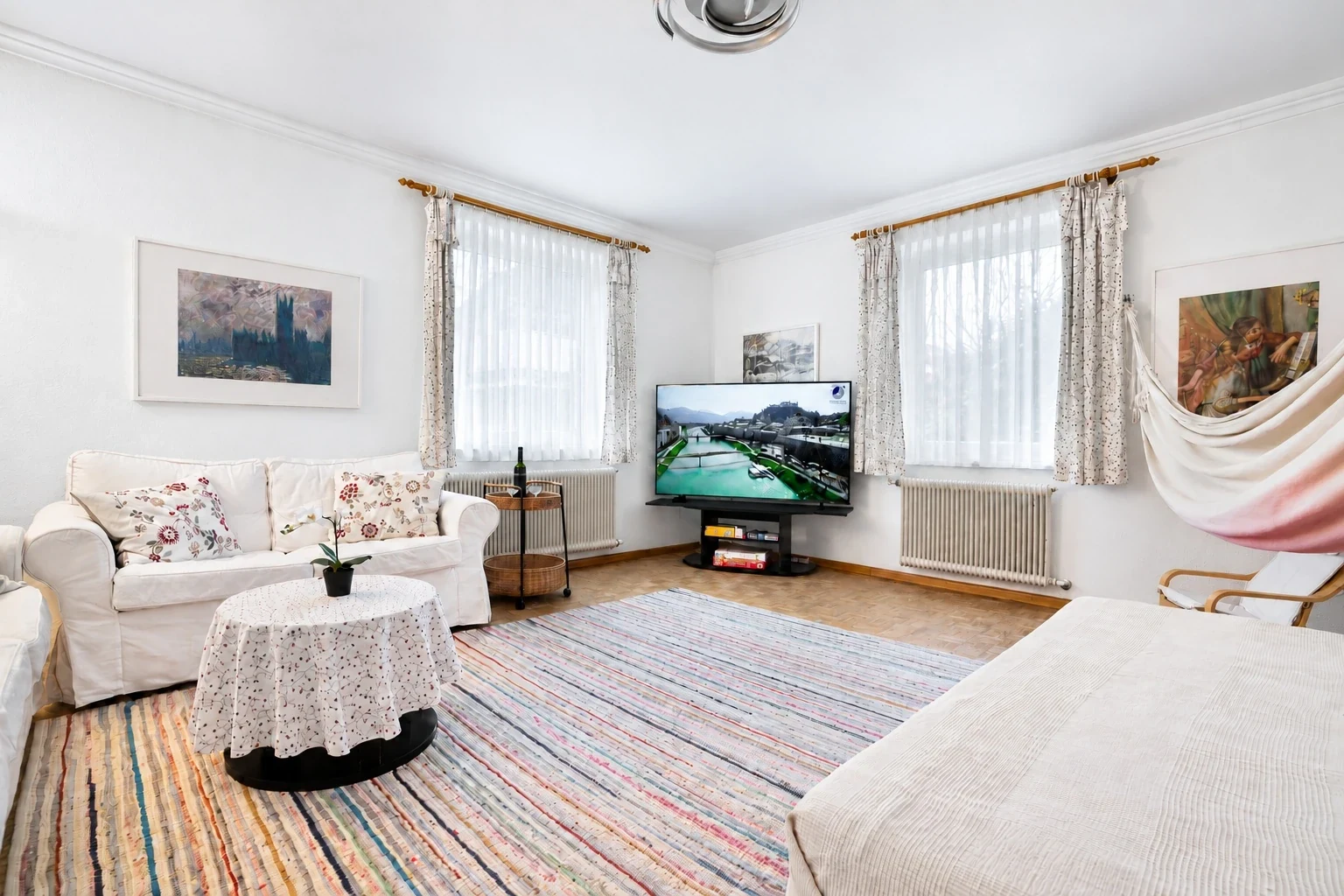 Wohnzimmer mit weißen Sofas, Fernseher und Hängematte