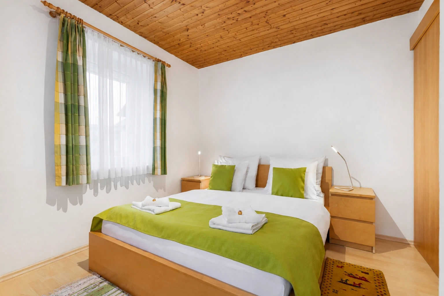 Schlafzimmer mit Doppelbett und grüner Tagesdecke